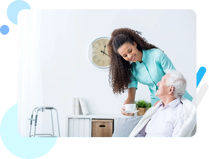 A woman is helping an older man in his chair.